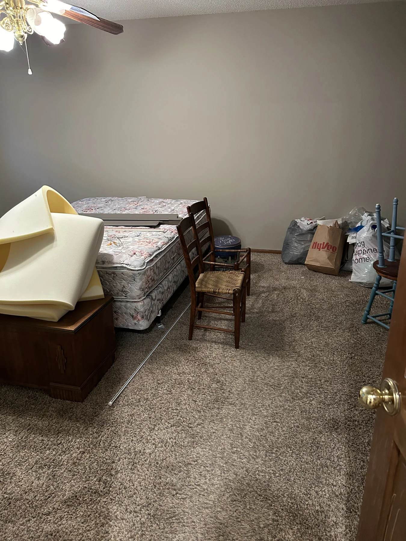 A bedroom partly cleared, with a mattress, chairs, and bagged items left to sort