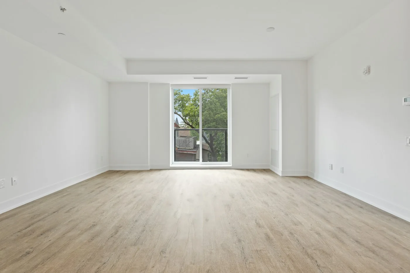 Empty white room with wood flooring and glass patio doors