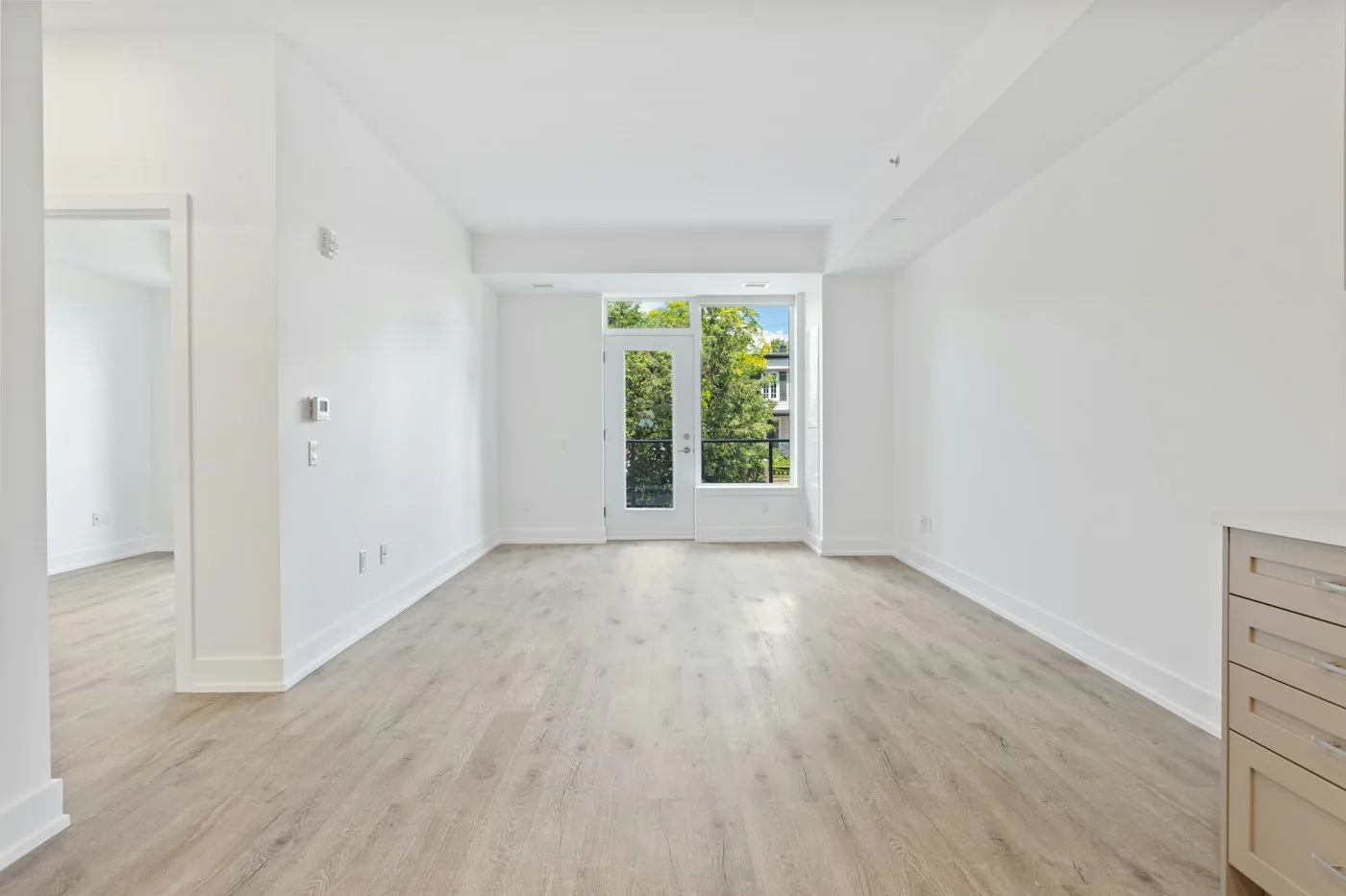 Bright empty room with an open doorway and tall windows