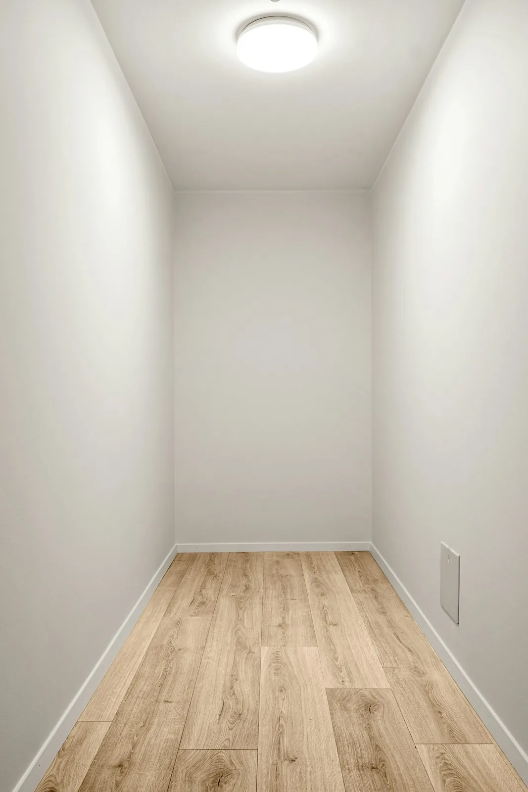 Small empty room with pale walls and wood flooring