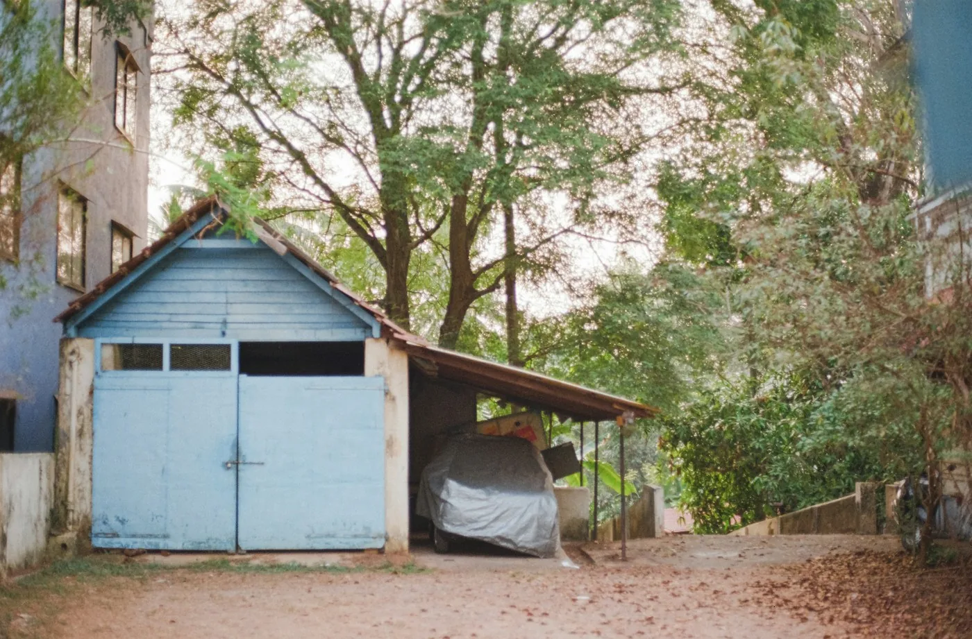 Blue home garage beside a covered car and bicycle