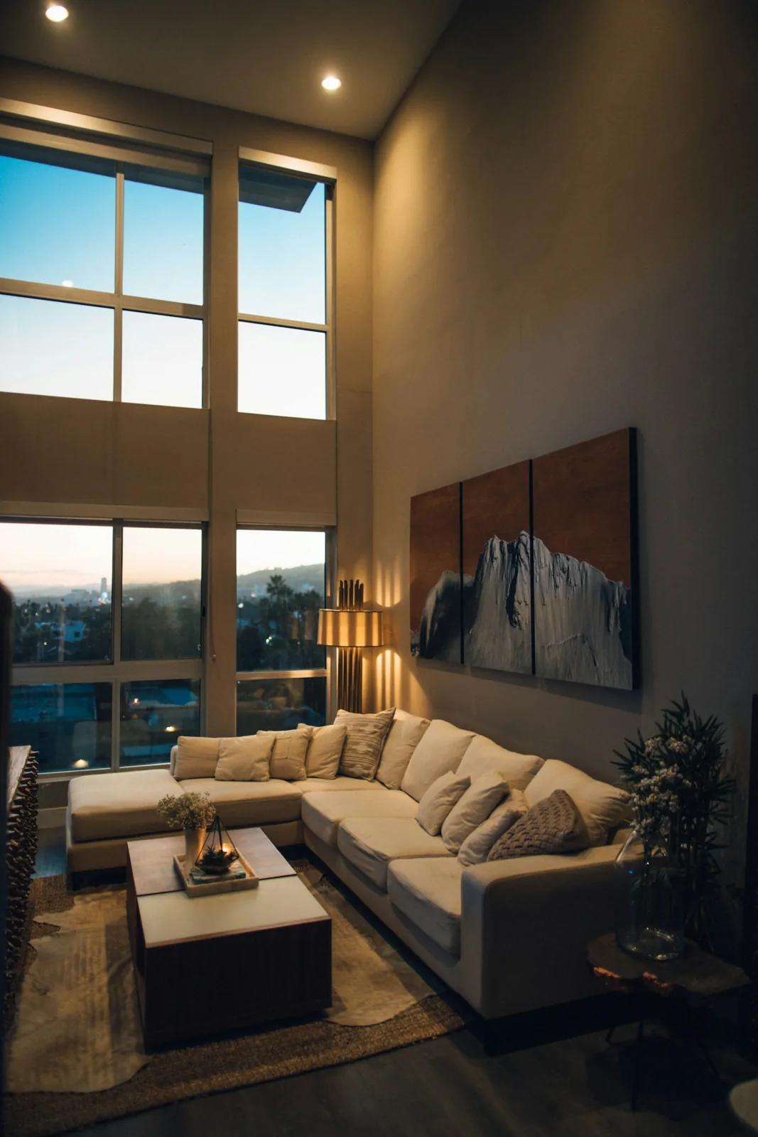 Living room with a sectional sofa and tall windows at sunset