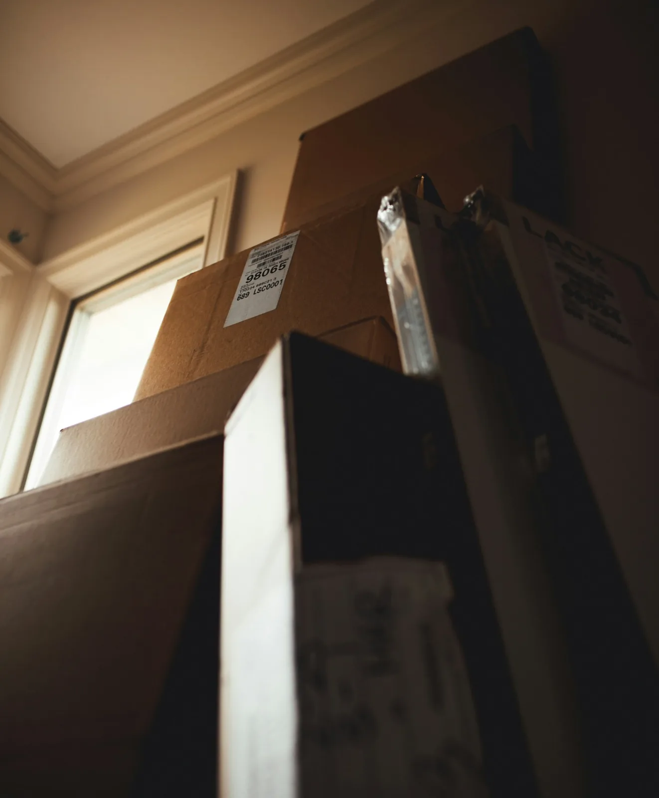 Tall stack of taped boxes beside a home window